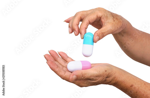 Old female hand holding two big capsule medicine islated on white background / Drug overdose concept