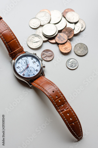 Time is money, time value of money concept : Coins and vintage brass pocket watch, idea of time which is a valuable commodity or resource and it's better to do work or things as quickly as possible