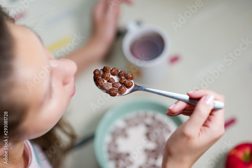 Girl is going to eat a portion of chocolate cereal with milk