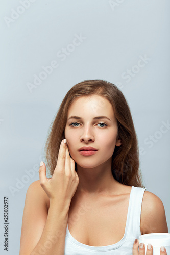 Beauty Concept. woman holds a moisturizer in her hand and spreads it on her face to moisturize her skin and wrinkle from impurities. body care, skincare.Taking good care of her skin