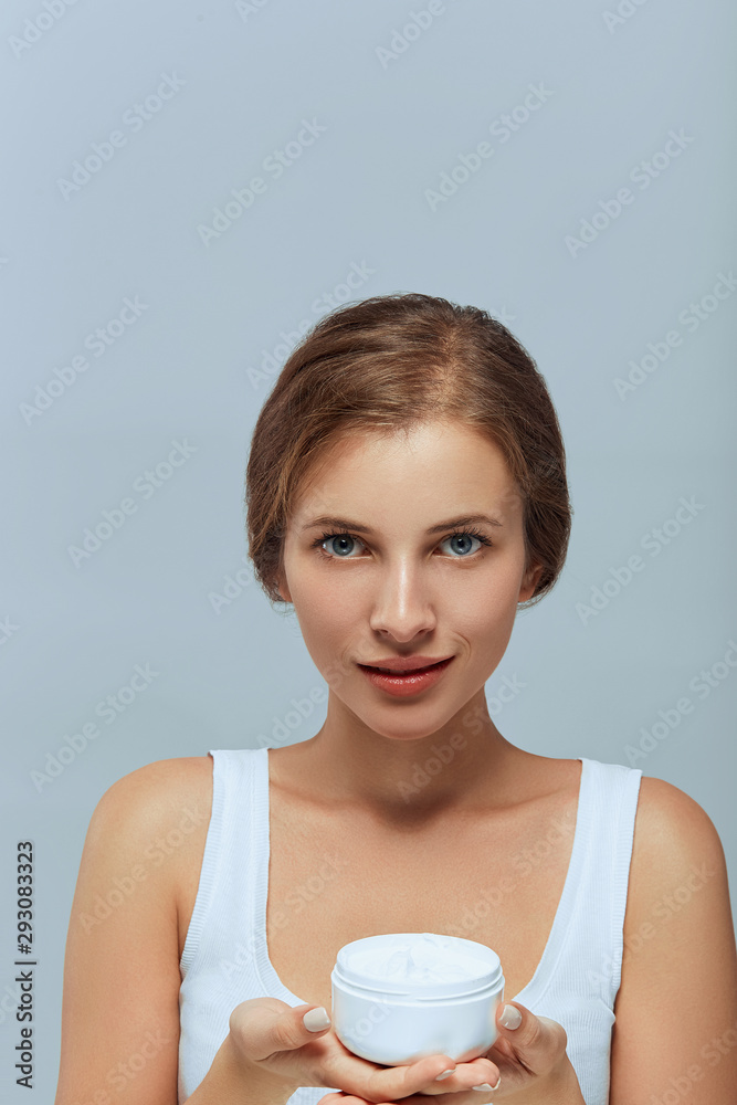 Beauty Woman Face Skin Care. Portrait Of Attractive Young Female Applying Cream And Holding Bottle. Closeup Of Smiling Girl With Natural Makeup And Fresh Skin. Cosmetics. Beauty Woman Face Skin Care. Portrait Of Attractive Young Female Applying Cream And Holding Bottle. Closeup Of Smiling Girl With Natural Makeup And Fresh Skin. Cosmetics.