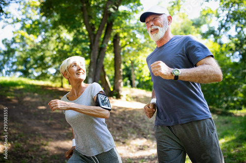 Mature or senior couple doing sport outdoors, jogging in a park