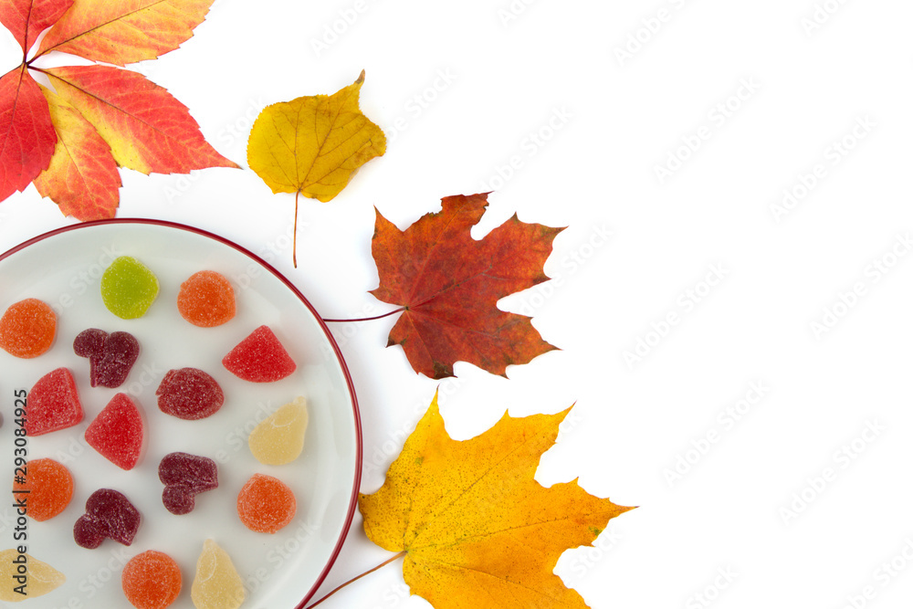 Plate with marmalade and Dry colorful leaves on a white background.