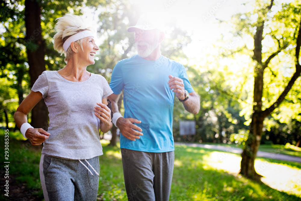 Beautiful senior couple running outside in forest Beautiful senior couple running outside in forest