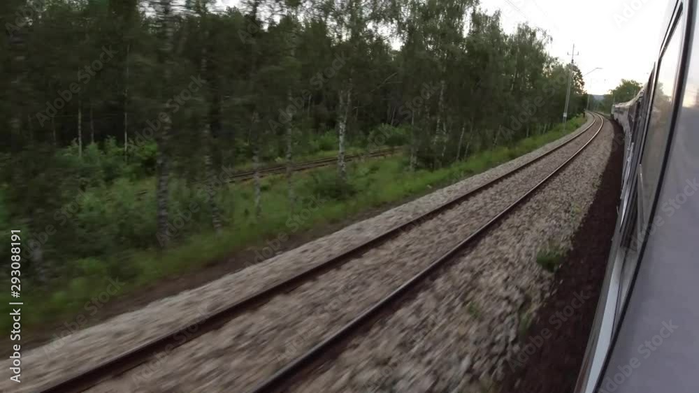 Looking out the window of a moving train. A view of the train tracks and the woods Looking out the window of a moving train. A view of the train tracks and the woods