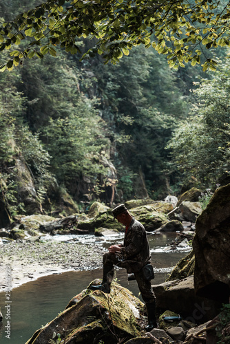 side view of soldier in military uniform near flowing water in woods