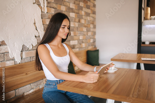 Beautiful girl use tablet in cafe. Female watch online. Student in cafe using wifi