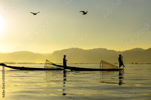 Fotografie Two Burmese men paddle their legs Came out to find fish in the morning on Inle Lake, Myanmar