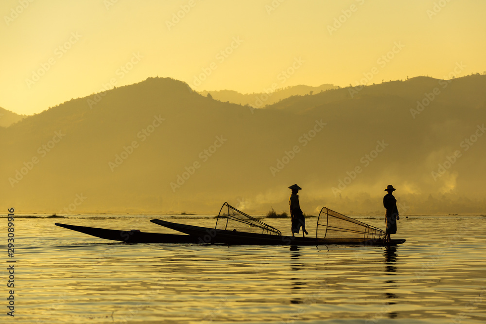 Two Burmese men paddle their legs Came out to find fish in the morning on Inle Lake, Myanmar.