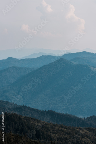 mountains with green trees against sky with clouds