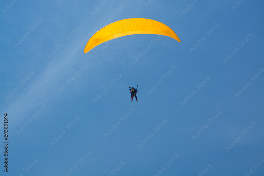 Skydiver with a yellow parachute on a background of blue clear sky Skydiver with a yellow parachute on a background of blue clear sky