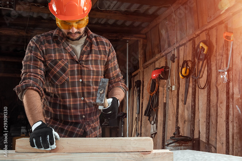 A man carpenter hammer a nail into a tree, male hands with a hammer close-up. Woodwork photo