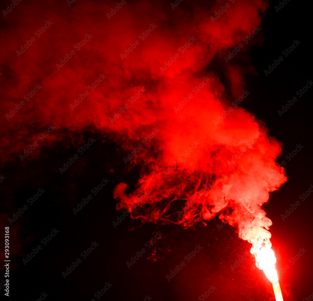 Naklejka Red smoke burns at night as a background