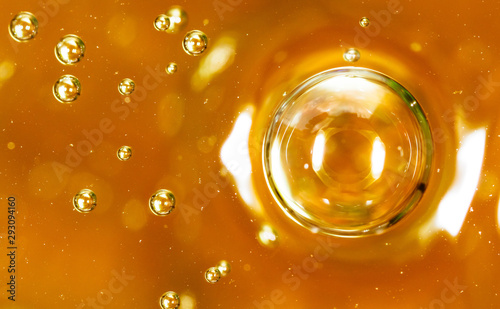 Bubbles of air on the smooth surface of golden water as an abstract background