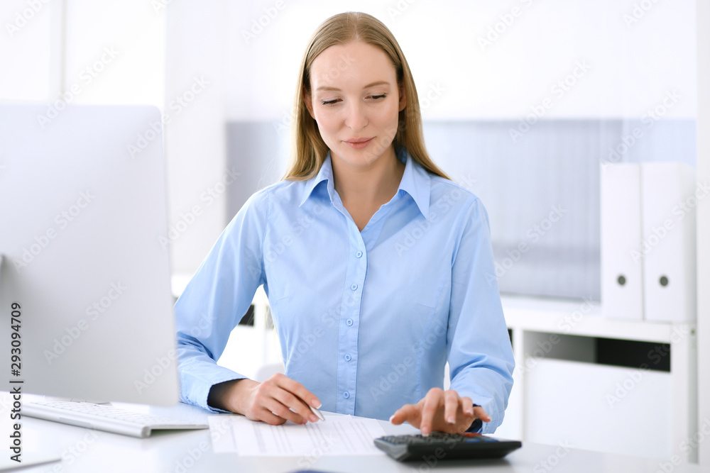 Accountant checking financial statement or counting by calculator income for tax form. Business woman sitting and working at the desk in office. Audit concept Accountant checking financial statement or counting by calculator income for tax form. Business woman sitting and working at the desk in office. Audit concept