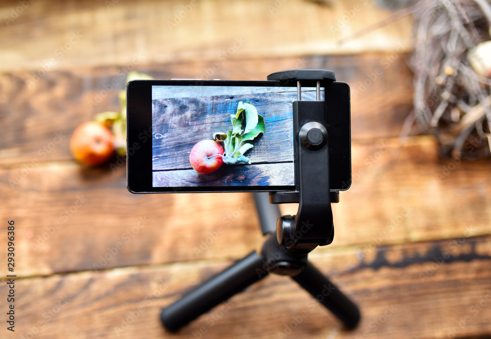 smartphone on a tripod photographs a still life with an Apple