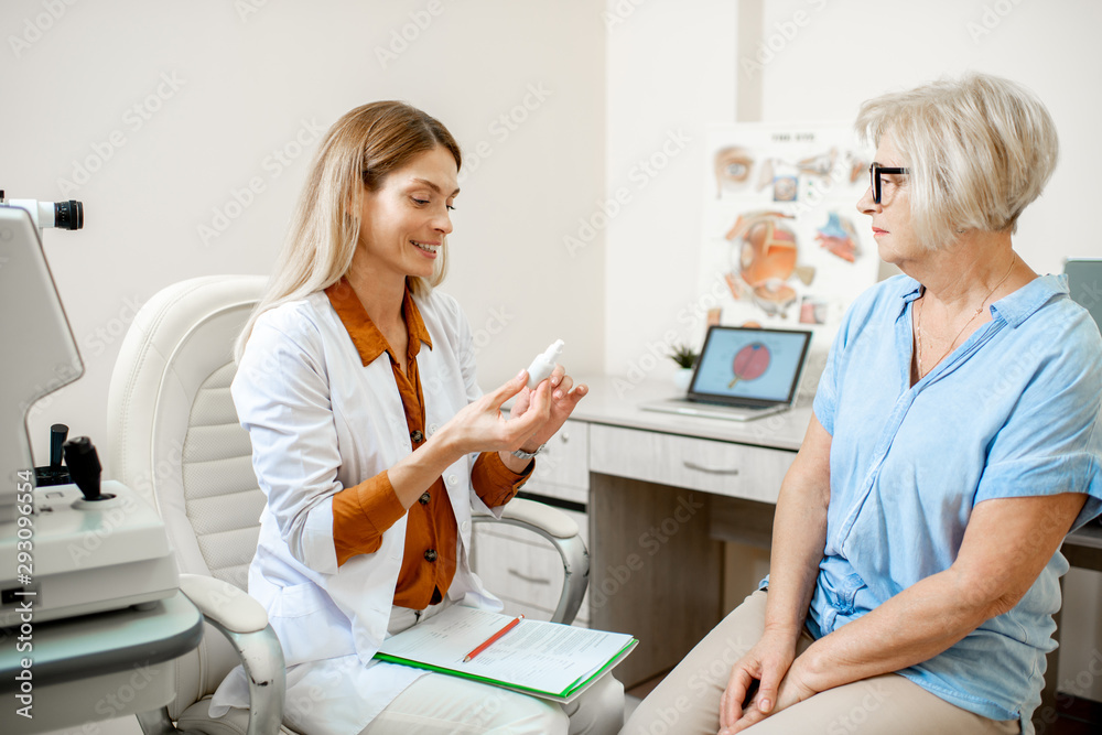 Senior woman patient talking with female ophthalmologist during a medical consultation at the ophthalmologic office. Doctor offering eye medcine for a patient Senior woman patient talking with female ophthalmologist during a medical consultation at the ophthalmologic office. Doctor offering eye medcine for a patient