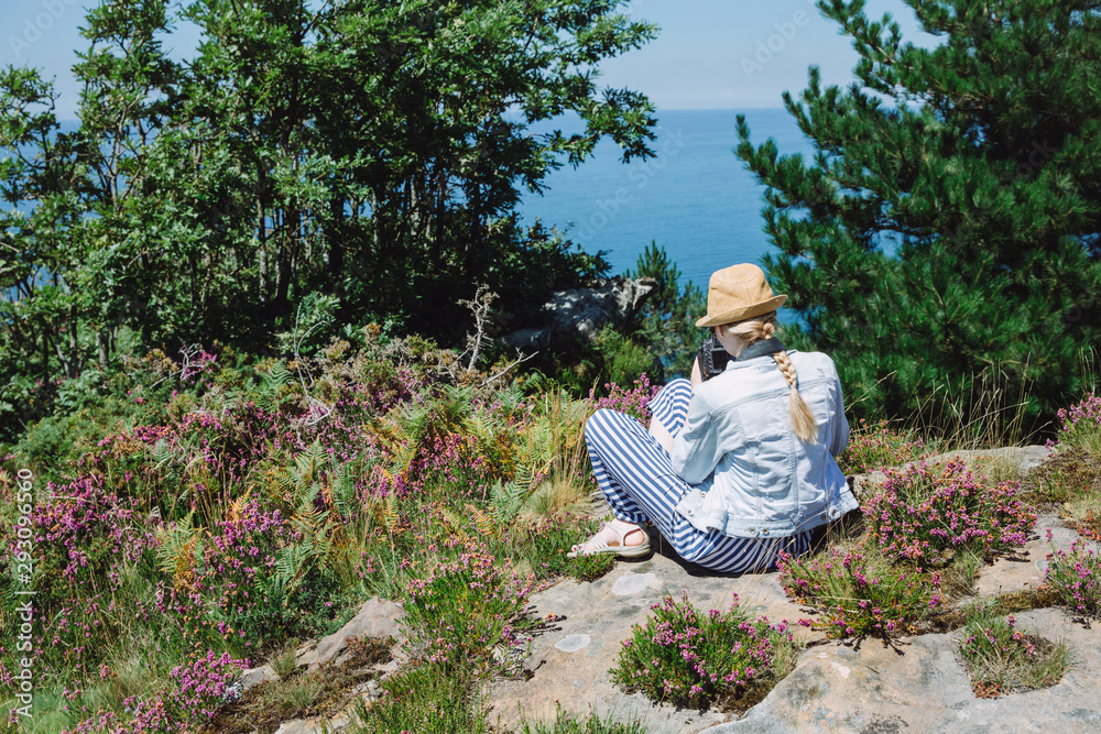 Woman taking picture of flowers on the cliff Woman taking picture of flowers on the cliff