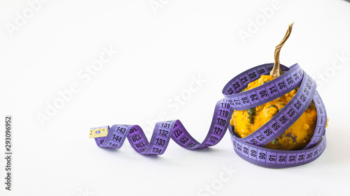 Pumpkin for weight loss with purple centimeter tape on a white background - Pumpkin for weight loss isolated on white. fitness diet