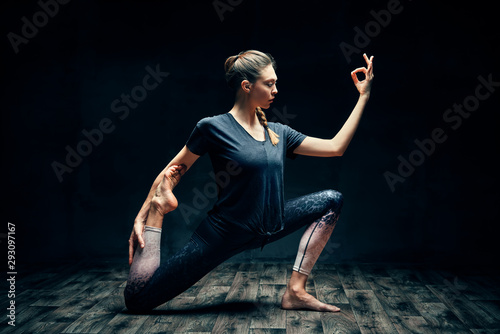 Young beautiful woman doing yoga asana one legged king pigeon pose in dark room