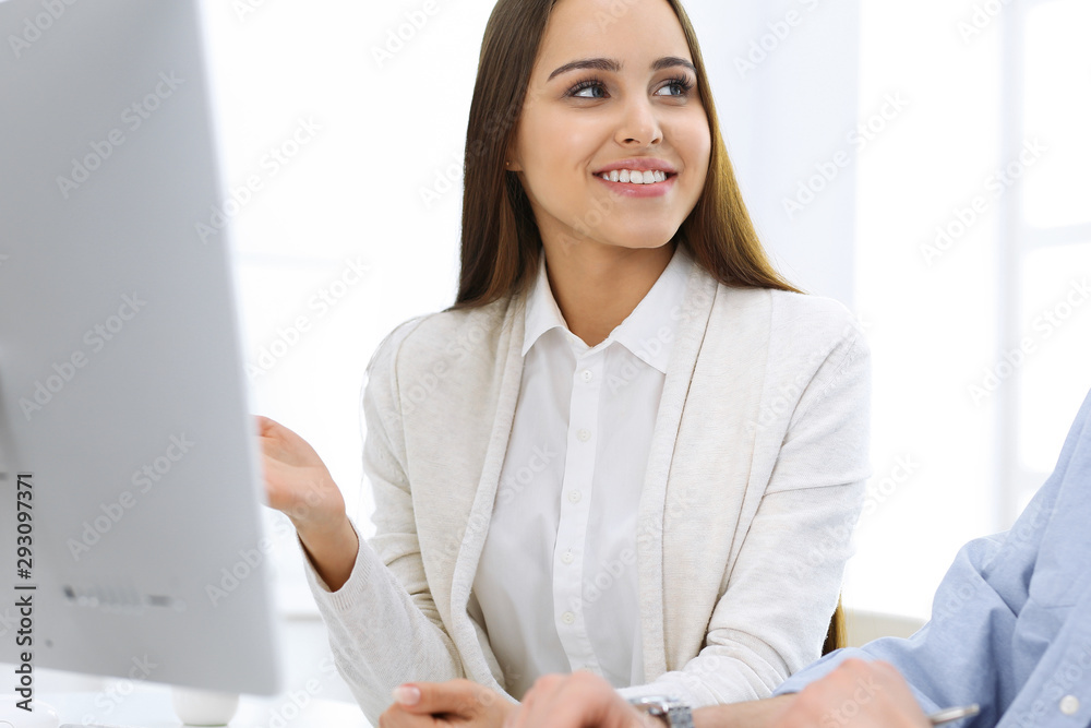 Business woman and man sitting and working with computer in office. Colleagues discussing something at meeting. Corporate teamwork and partnership concepts
