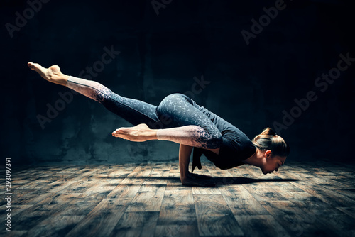фотографія Young woman practicing yoga doing hurdler pose in dark room