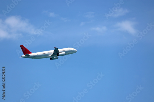 Airplane flying in the blue sky on background of white clouds, side view. Two-engine commercial plane during the turn, turbulence and travel concept