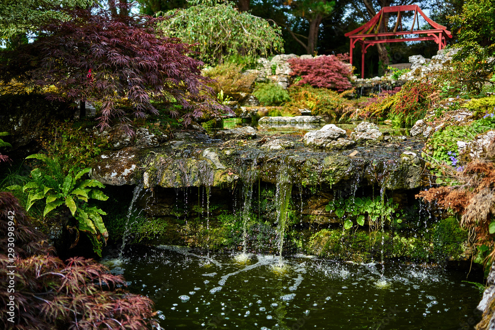 Waterfall in a beautiful Japanese garden with the outline of a pagoda in the background