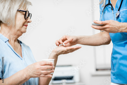 Nurse giving some medicine for a senior woman sitting on the couch, taking care of elder patients in the hospital