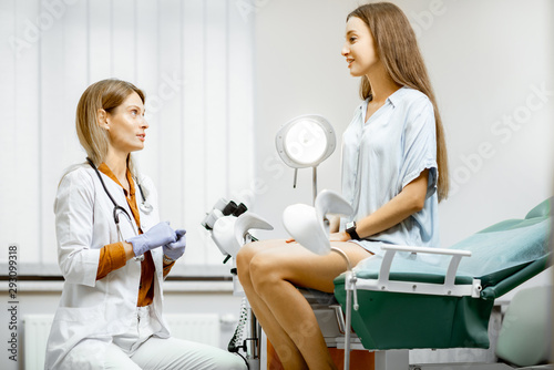 Gynecologist preparing for an examination procedure for a pregnant woman sitting on a gynecological chair in the office photo