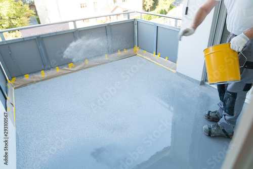 construction worker renovates balcony floor and spreads chip floor covering on resin and glue coating before applying water sealant photo