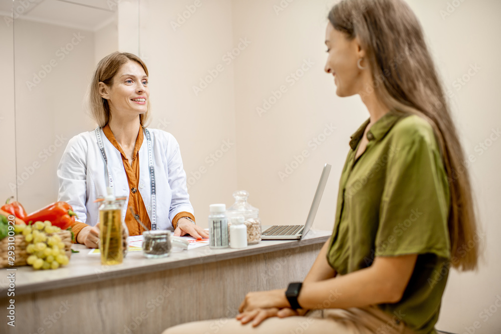 Nutritionist with young woman client talking about meal plan and healthy products during a medical consultation in the office Nutritionist with young woman client talking about meal plan and healthy products during a medical consultation in the office
