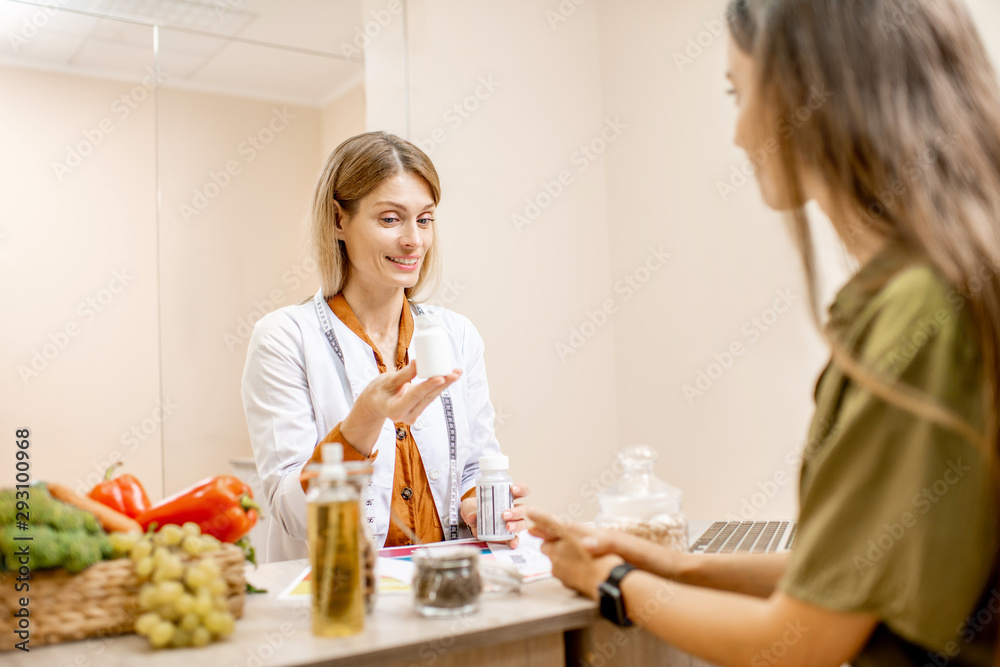 Nutritionist with young woman client talking about meal plan and healthy products during a medical consultation in the office Nutritionist with young woman client talking about meal plan and healthy products during a medical consultation in the office