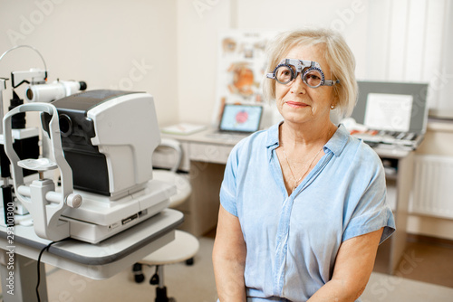 Senior woman checking vision with eye test glasses during a medical examination at the ophthalmological office