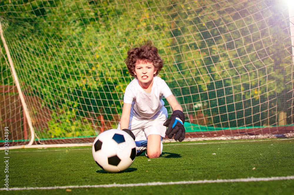 Fototapeta premium Summer soccer tournament for young kids. football club. emotions and joy of the game. Young goalie. Kids - soccer champion. Boy goalkeeper in football sportswear on stadium with ball. Sport concept.