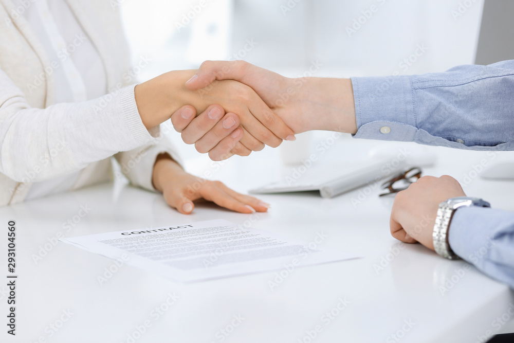 Business people shaking hands at meeting or negotiation after contract discussing. Businessman and woman handshake at office while sitting at the desk. Success concept