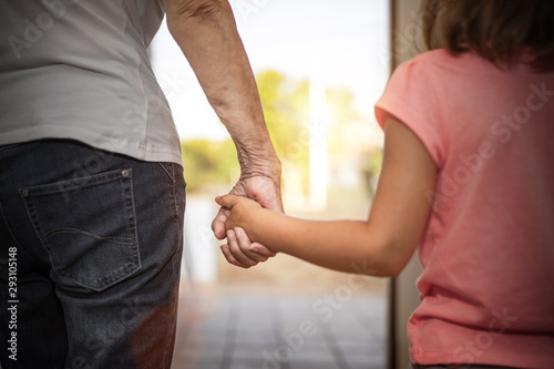 older person grabs a little girl's hand photo