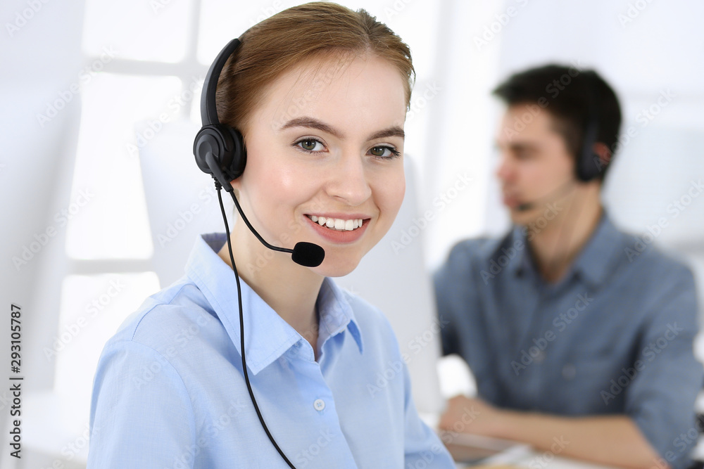 Group of operators at work. Call center. Focus on beautiful woman receptionist in headset at customer service. Business concept and casual clothing style Group of operators at work. Call center. Focus on beautiful woman receptionist in headset at customer service. Business concept and casual clothing style
