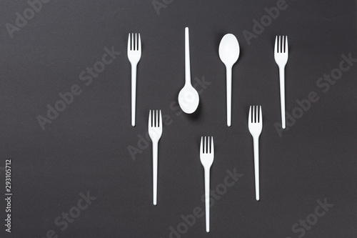 Plastic forks and spoons on gray background