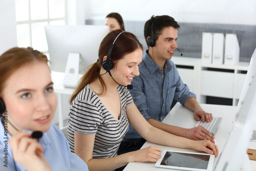 Group of operators at work. Call center. Focus on beautiful woman receptionist in headset at customer service. Business concept and casual striped clothing style Group of operators at work. Call center. Focus on beautiful woman receptionist in headset at customer service. Business concept and casual striped clothing style