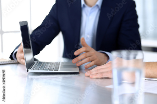 Business people using laptop computer while working together at the desk in modern office. Unknown businessman or male entrepreneur with colleague at workplace. Teamwork and partnership concept