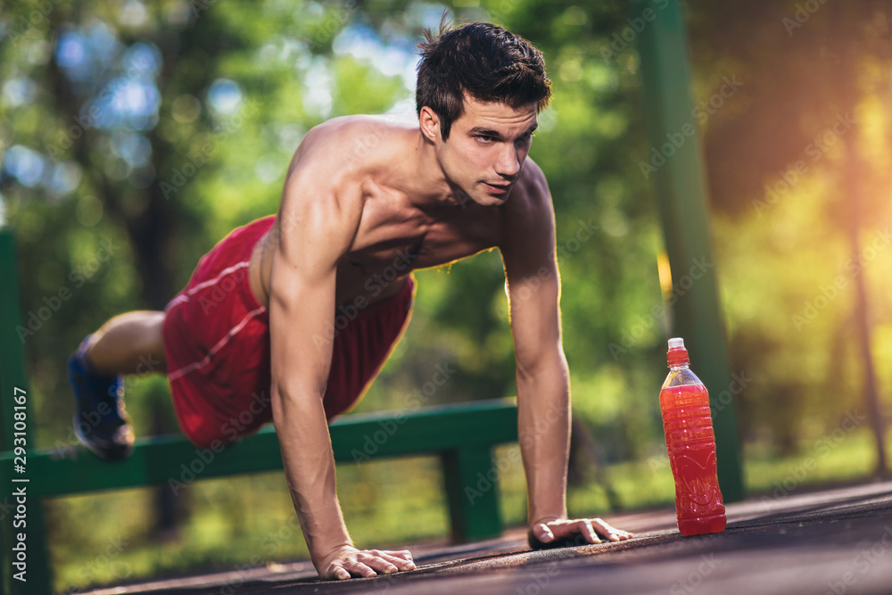 Fototapeta premium Picture of a young athletic man doing push ups outdoors.
