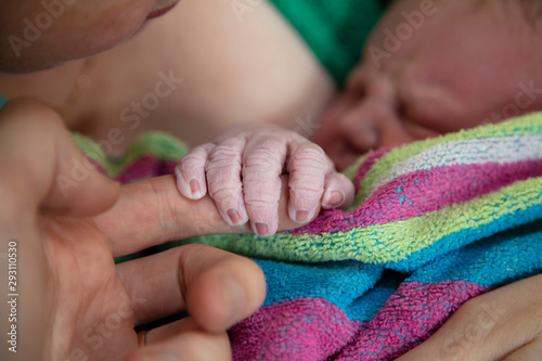 A newborn baby holds onto their fathers finger after being born