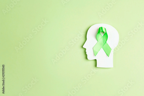 World mental health day concept. Green awareness ribbon with brain symbol on a green background.