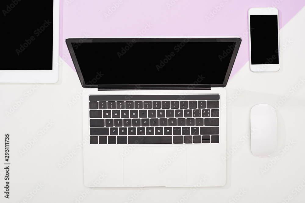 flat lay with laptop, digital tablet, smartphone with blank screen and computer mouse on violet and white background