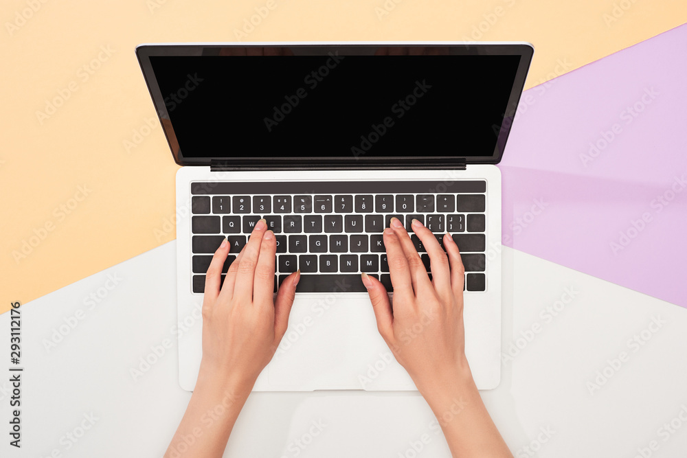 cropped view of woman using laptop on beige, violet and white background cropped view of woman using laptop on beige, violet and white background