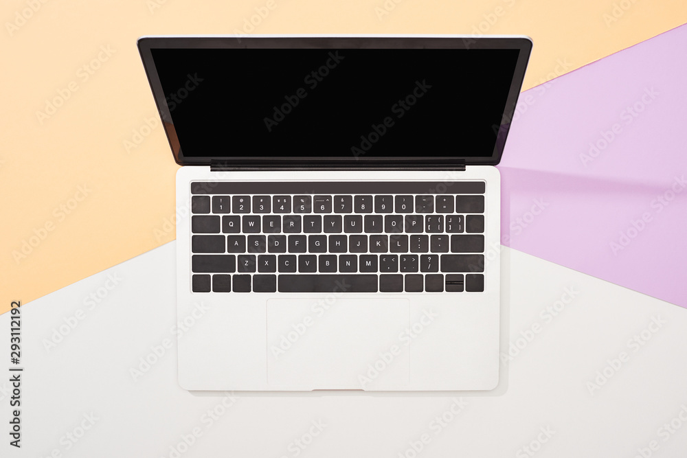 top view of laptop with blank screen on beige, violet and white background top view of laptop with blank screen on beige, violet and white background