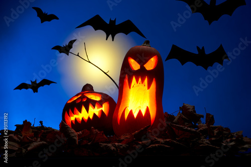 Photo of two pumpkins with burning mouths, bats at night