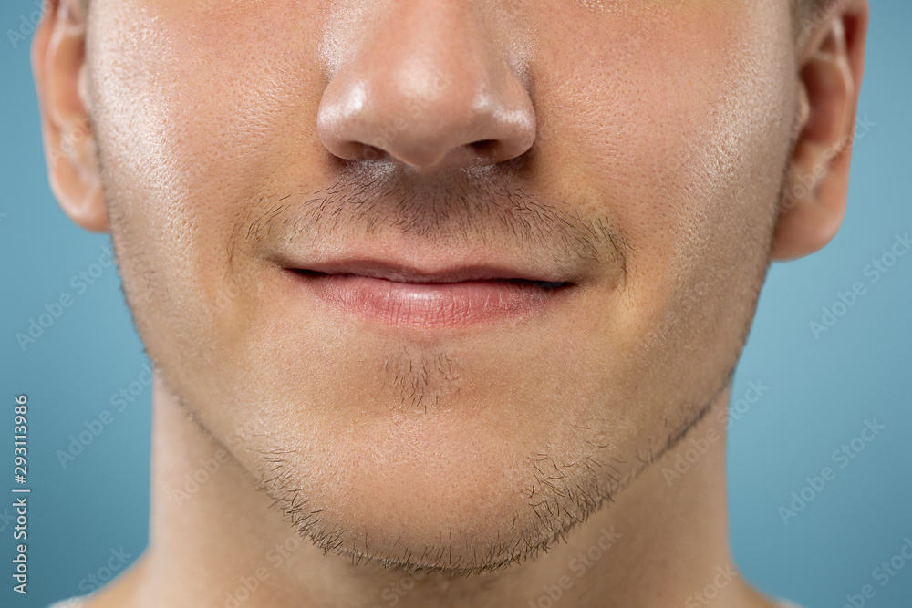 Caucasian young man's close up portrait on blue studio background. Beautiful male model with well-kept skin. Concept of human emotions, facial expression, sales, ad, beauty. Lips and cheeks. Caucasian young man's close up portrait on blue studio background. Beautiful male model with well-kept skin. Concept of human emotions, facial expression, sales, ad, beauty. Lips and cheeks.