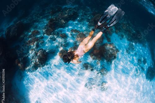 Slim woman freediver swim with fins underwater. Freediving in blue sea